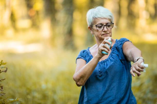 senior mujer uso de repelente de insectos en el bosque - insect repellant mosquito bug bite spraying fotografías e imágenes de stock