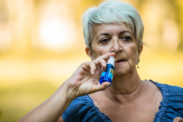 istock Senior woman having flu using nasal spray to help herself. 1273339600