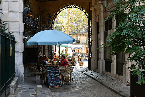 Paris, France-09 16 2020: Customers seated at tables of a sidewalk café located in a small alley, Paris France.