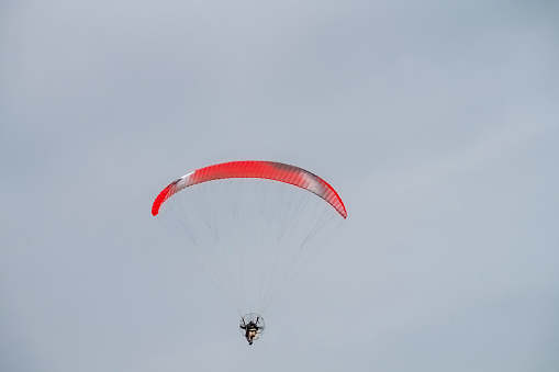 A powered paraglider over Hunstanton beach on an overcast day.