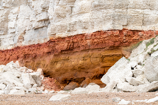 The chalk and sandstone cliffs are constantly being eroded and collapsing on to the beach.  This shows the different coloured rock strata and a pile of collapsed rocks on the beach.