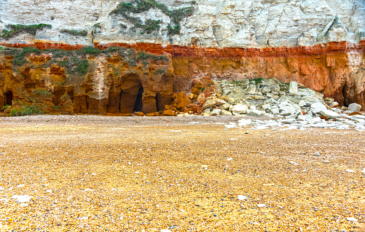 The chalk and sandstone cliffs are constantly being eroded and collapsing on to the beach.  This shows the different coloured rock strata and a pile of collapsed rocks on the beach.