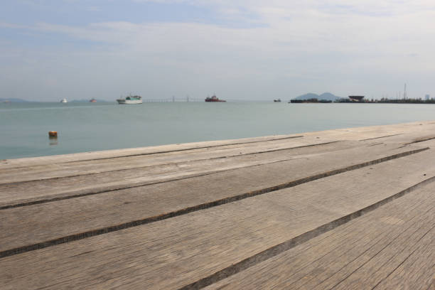 Low angle view through a wooden pier to the ocean Low angle view through a wooden pier to the ocean, harbor and cloud sky in Georgetown, Penang, Malaysia parallel port stock pictures, royalty-free photos & images