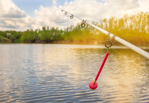 Fishing spinning rod with a bright pink bite indicator close-up. Fishing on the reservoir. High quality photo