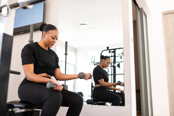 istock Young woman in gym doing biceps curls with dumbbells 1273345237