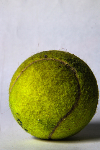 Old green tennis ball with a white background