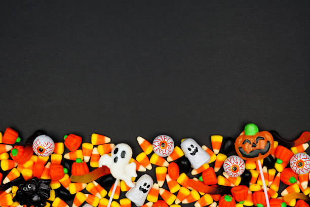 Halloween candy bottom border on a black background Halloween candy bottom border. Top view on a black background with copy space. eye candy stock pictures, royalty-free photos & images