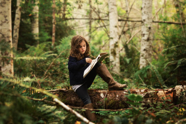 istock Girl reading book on log 1273353614