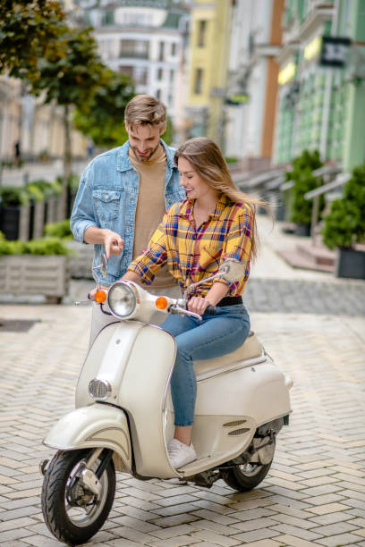 istock Man instructing woman to ride a scooter 1273354091