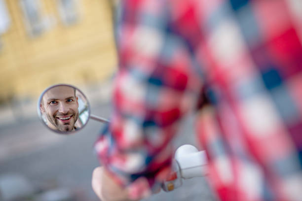 Back view. A man looking at his scooters looking at the rear-view mirror