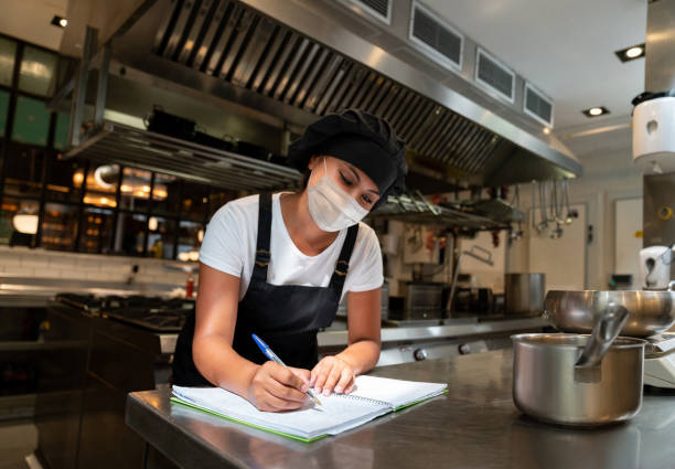 Happy chef working at a restaurant wearing a facemask in the kitchen