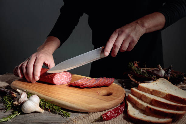 istock Man cuts a sausage for a sandwich. 1273355914