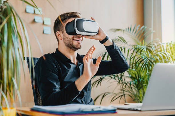 istock Future concept. Handsome young man in VR headset gesturing and smiling while sitting in office 1273360066