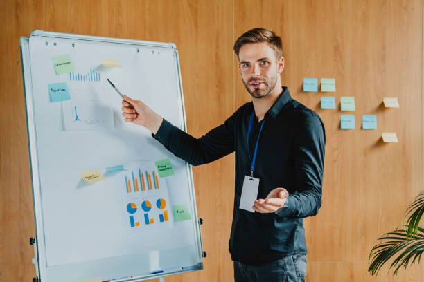 istock Young man explains business data on white board in casual office room. Teleworking 1273360531