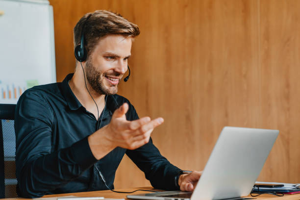istock Young caucasian man in headset explaining emotionally sitting in front of laptop computer. 1273360629
