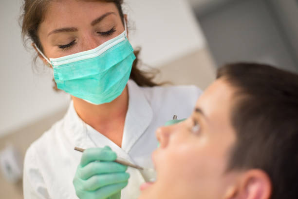 Dentist examining teeth of female patient.