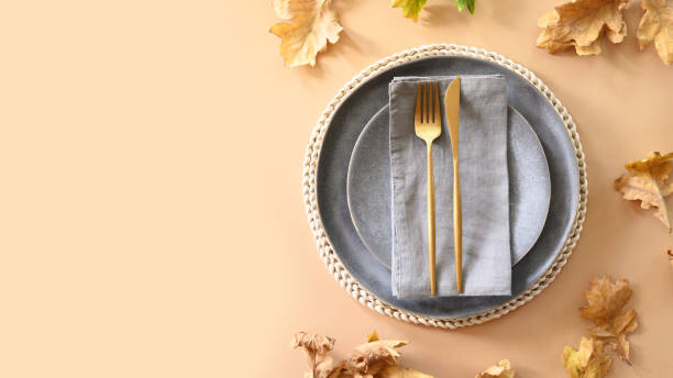 istock Autumn table setting decorated dry oak leaf and golden cutlery on grey table for Thanksgiving day. View from above. 1273363588