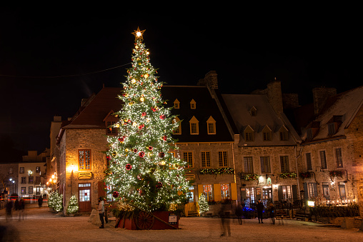Quebec, Canada - December 25, 2019. Visitors around Christmas tree at night at town square in historic district of Quebec City, Canada