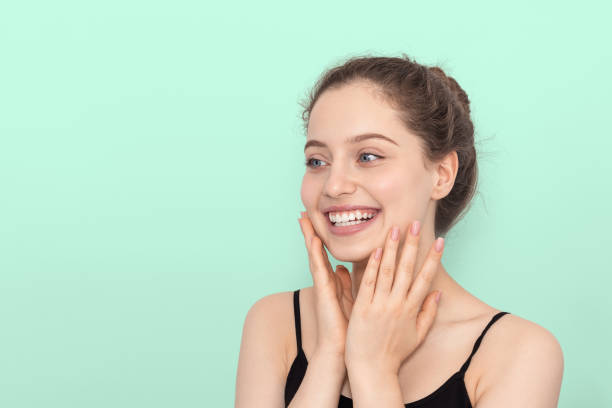 istock The girl smiles, touches her face with her hands. 1273367863