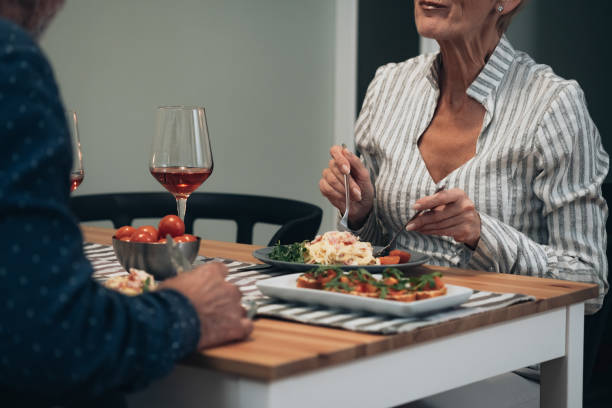 cheerful couple have romantic dinner at home stock photo - eating senior adult color image spaghetti imagens e fotografias de stock