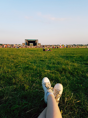 Relaxing at open air music festival in Ukraine. Traditional celebration with famous music groups performing on stage. Listening to live music looking at crowd when laying down on the green grass lawn.
