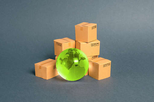 Green glass planet globe and a pile of cardboard boxes. Business and industry, transport infrastructure. The concept of commerce and trade, cargo delivery, exchange of goods. Globalization, markets.