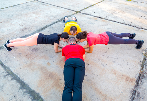 Young fit sports people practicing plank position outdoors