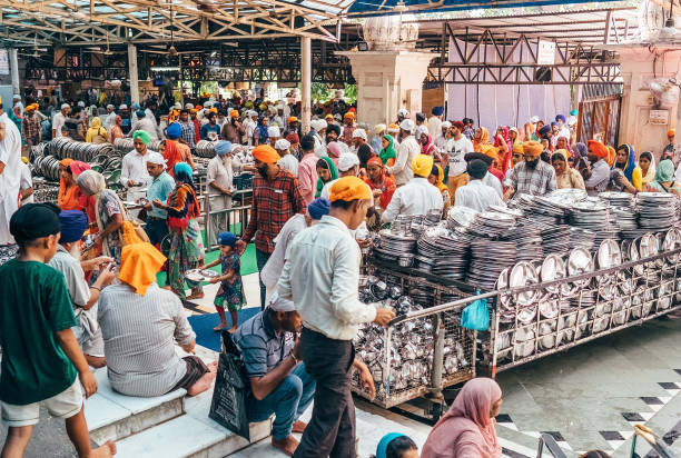 peregrinos as pessoas entram e saem da cantina livre em amritsar. este é o maior restaurante gratuito do mundo em golden temple, amritsar, índia - men group of objects entrance hall group of people - fotografias e filmes do acervo