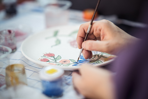 Painting flowers on a ceramic plate with a paintbrush