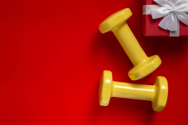 istock sports composition with dumbbells and red gift box with white bow on red background. 1273381678