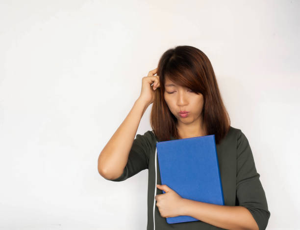 istock Lady hugging book in her arm,raise finger touch her head and thinking,with confuse feeling,model posing 1273381764