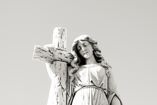 Black and white Old statue of angle with cross in cemetery build in 1877 Sydney Australia, looking down, background with copy space, horizontal composition