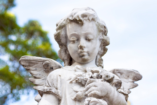 Old statue of little angle with flowers in cemetery build in 1877 Sydney Australia, background with copy space, horizontal composition