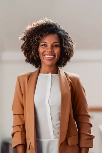 Portrait of young cheerful african american woman wearing brown suit smiling and looking at camera
