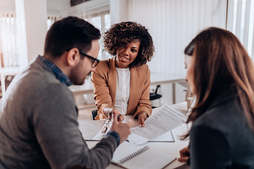 Couple sitting at the desk in the bank and signing loan agreement