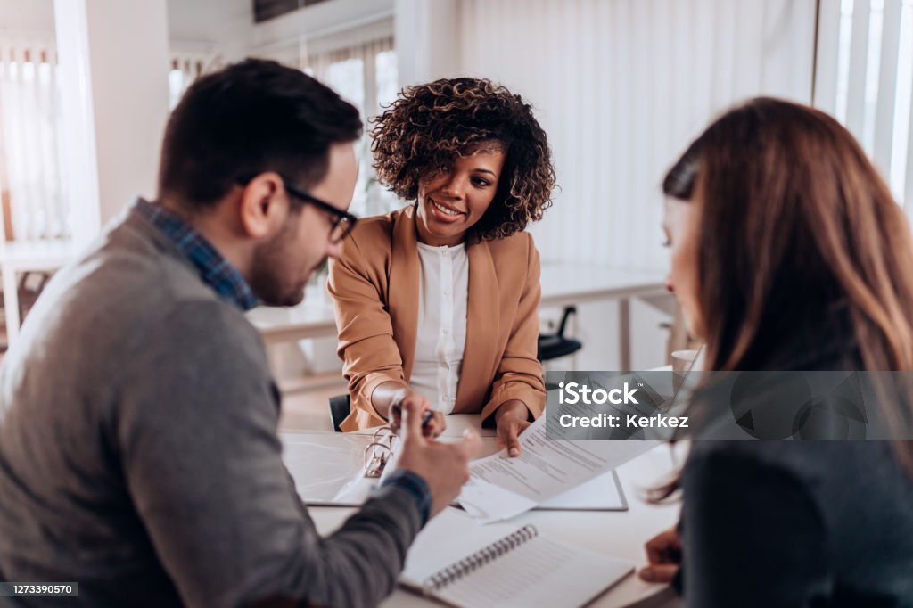 Couple signing loan agreement at the bank Couple sitting at the desk in the bank and signing loan agreement Insurance Agent Stock Photo
