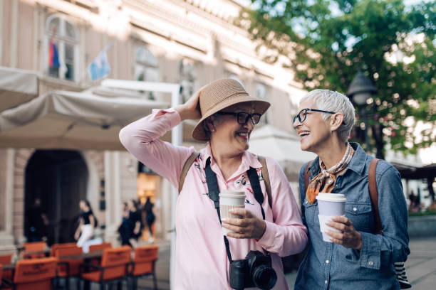 istock Two senior friends on a journey walking, drinking coffee and having fun 1273391755