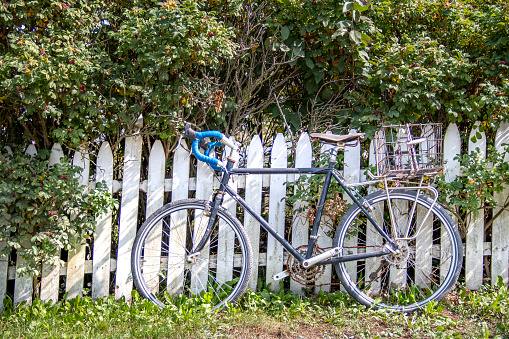 a picture of a Black bicycle in front of a white wooden fence