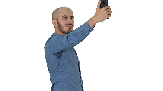 Medium shot. Side view. Selfie time! Handsome young man taking selfie with his phone on white background. Professional shot in 4K resolution. 011. You can use it e.g. in your commercial video, business, presentation, broadcast