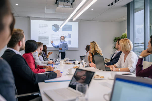 istock Mature businessman giving presentation to executive team 1273400289