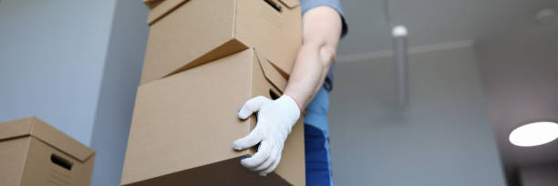 istock Man work clothes and gloves carries cardboard boxes 1273400501