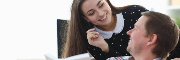 istock Guy is sitting on couch with book, girl is smiling 1273400591