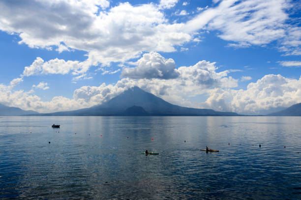 Aerial of fishing boats on Lake Atitlan in Guatemala with Toliman volcano in the background and fishing boats in the water early morning, during sunrise