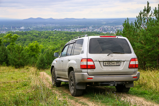Asha, Russia - August 8, 2020: Offroad car Toyota Land Cruiser 100 at the high mountain at the background of the town.