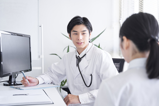 Un médico japonés que examina a una trabajadora de oficina photo