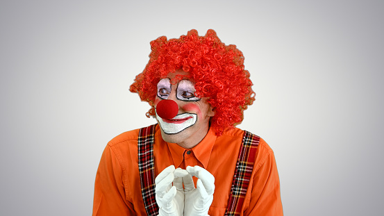 Photograph of person with red nose making gestures of approval. Concept of clowns.