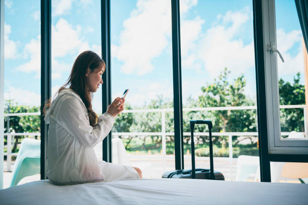 istock Young female traveller on bed using smartphone in hotel 1273412028