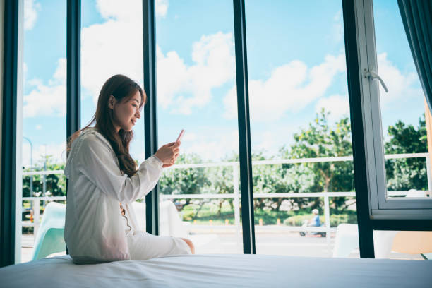 istock Young female traveller on bed using smartphone in hotel 1273412058