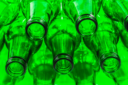 A sizable collection of green glass bottles neatly stacked on a shelf, likely awaiting industrial recycling or reuse. The bottles appear uniform in shape and color, creating a striking sight.