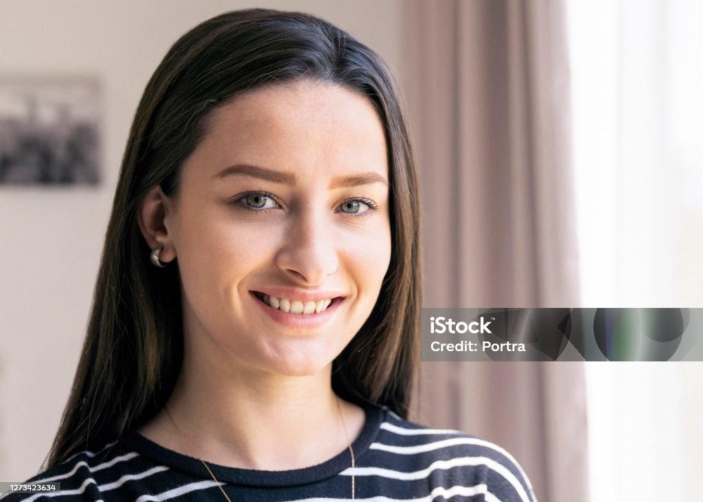 Smiling beautiful woman at home Close-up portrait of young woman. Beautiful female is at home. She is smiling. Gray Eyes Stock Photo